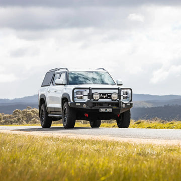 White 4x4 with IRONMAN 4x4 Deluxe bull bar parked in open grassland