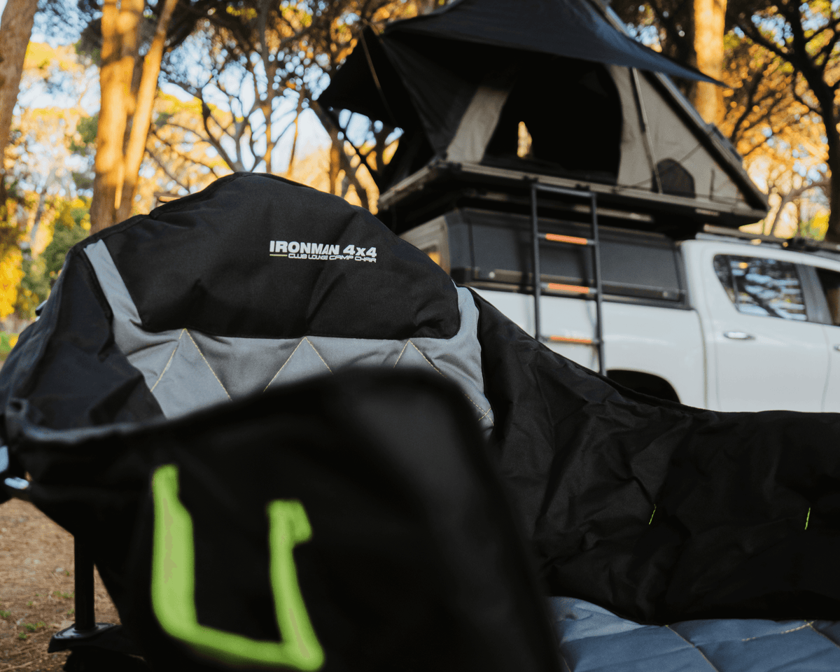 IRONMAN 4x4 Club Lounge quad fold camp chair beside a 4x4 with rooftop tent