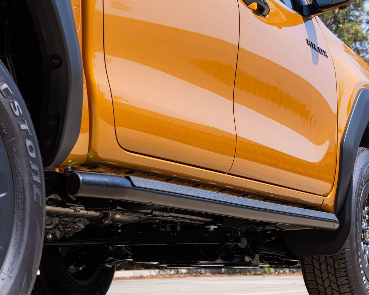 IRONMAN 4x4 premium side steps fitted to an orange Toyota Hilux Travo, close-up