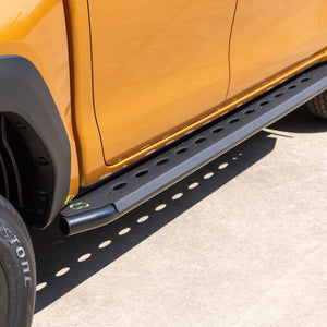 IRONMAN 4x4 side steps on an orange Toyota Hilux Travo, rear angle
