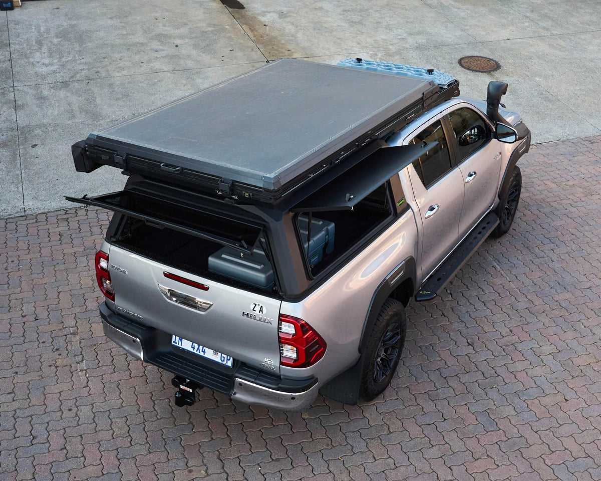 RAID Hybrid canopy on a silver Toyota Hilux GD-6 with side door open, aerial view