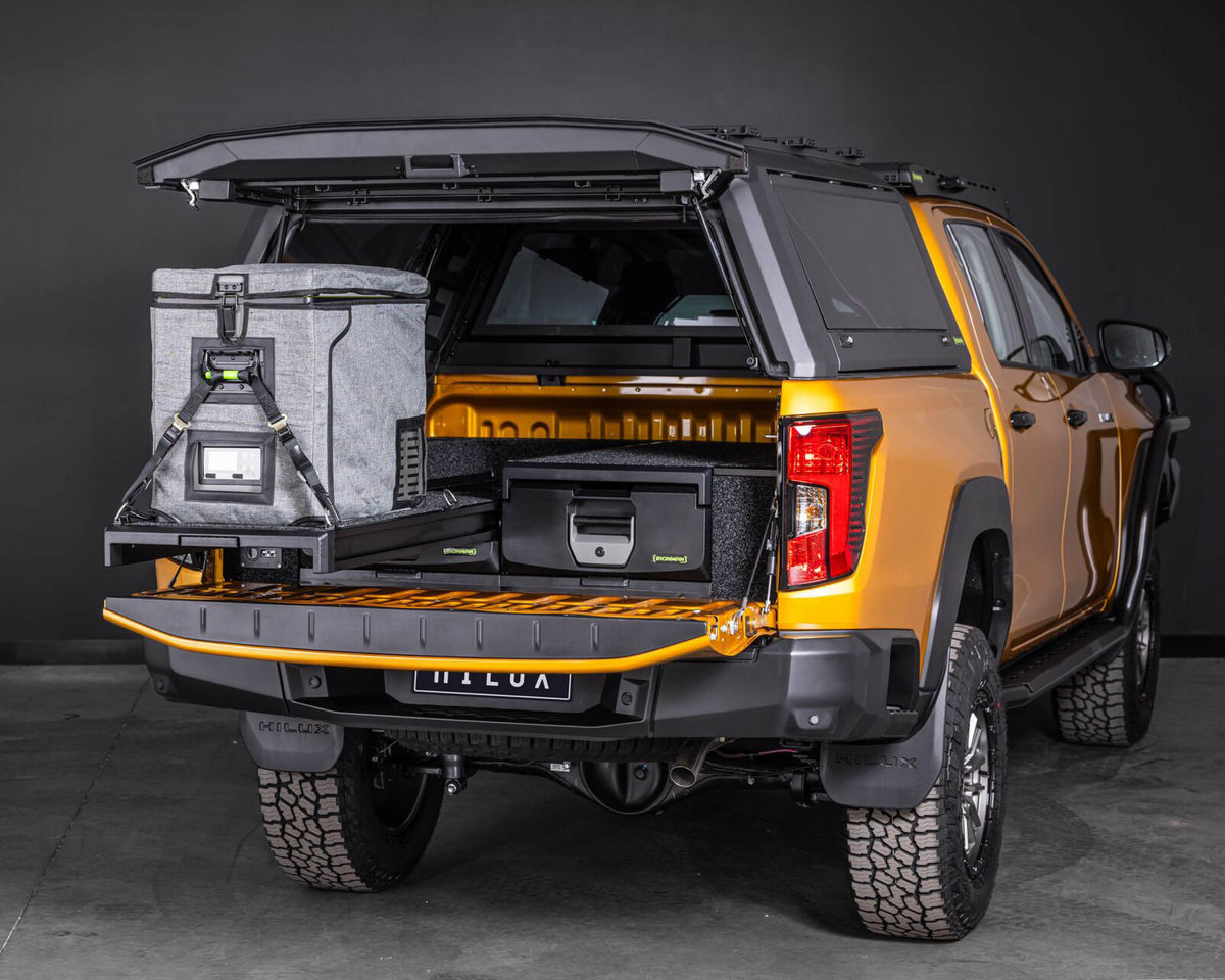 Rear three-quarter view of an orange Toyota Hilux with IRONMAN 4x4 drawers and a fridge slide