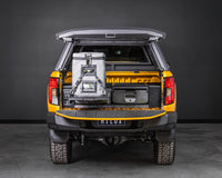 Orange Toyota Hilux canopy open, showing IRONMAN 4x4 drawers and a fridge on the slide