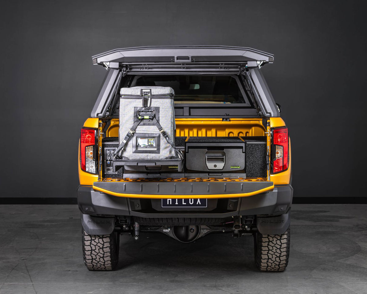 Orange Toyota Hilux canopy open, showing IRONMAN 4x4 drawers and a fridge on the slide