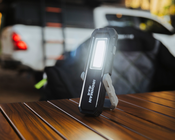 IRONMAN 4x4 rechargeable LED worklight standing on a table at camp