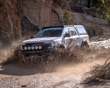 White Ford Ranger Next Gen with RAID Full Glass canopy splashing through a creek