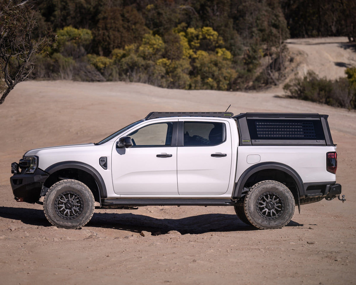 Side view of a white Ford Ranger Next Gen with RAID Full Glass canopy on a sand track