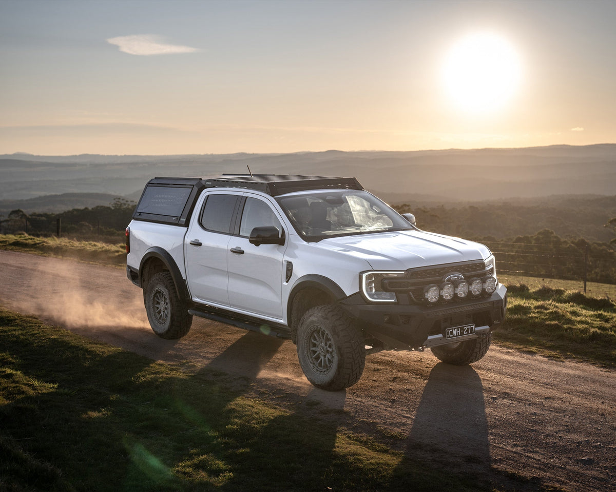 White Ford Ranger Next Gen with RAID Full Glass canopy driving at sunset