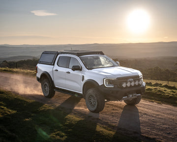 White Ford Ranger Next Gen with RAID Full Glass canopy driving at sunset