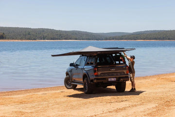 Deltawing 270 degree awning open on a grey 4x4 on the beach by a lake