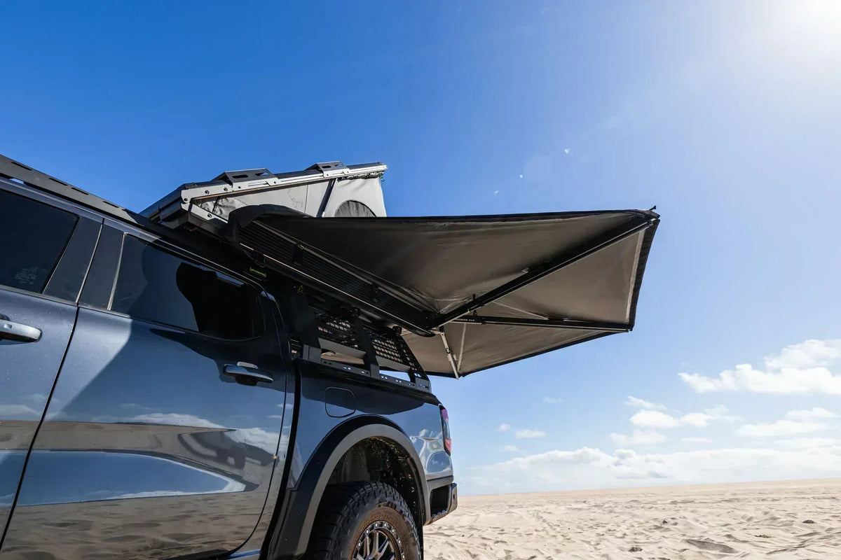 Deltawing 270 degree awning extended from a grey 4x4 on the sand