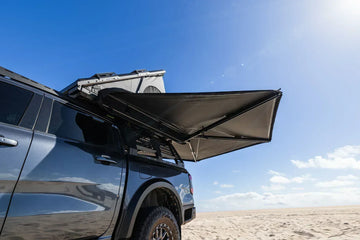Deltawing 270 degree awning extended from a grey 4x4 on the sand