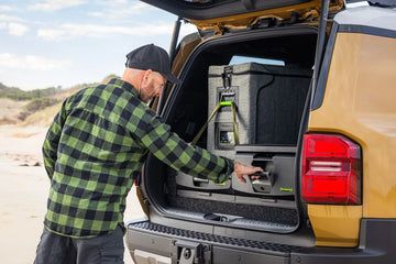 Man using an IRONMAN 4x4 drawer and fridge slide in the back of a Toyota Prado 250