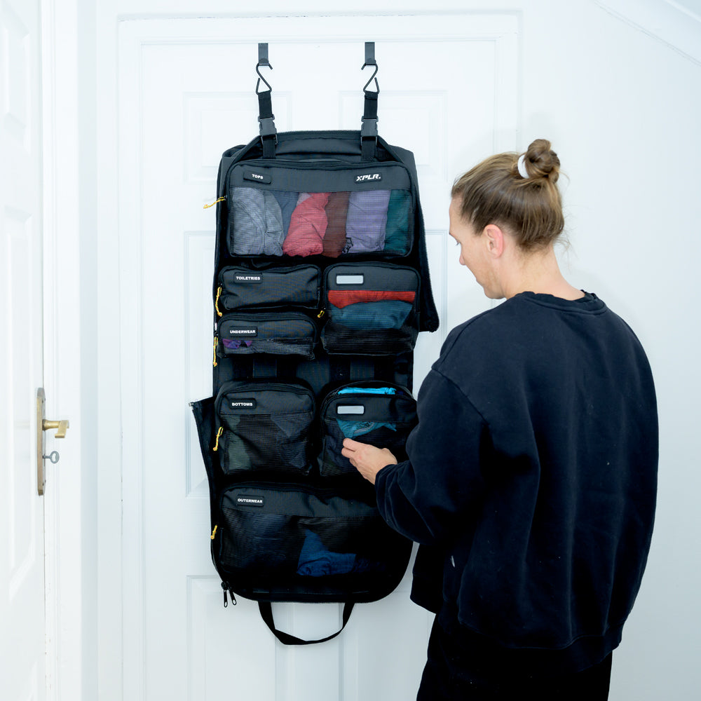 Woman using the XPLR Duffel modular travel bag hung on a door