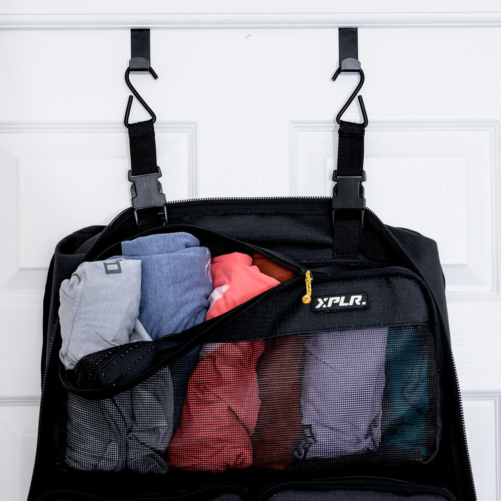 XPLR Duffel modular hanging travel bag packed with clothes, hung on a door