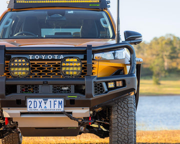IRONMAN 4x4 APEX bull bar fitted to a Toyota Hilux Travo by a lake, close-up front view