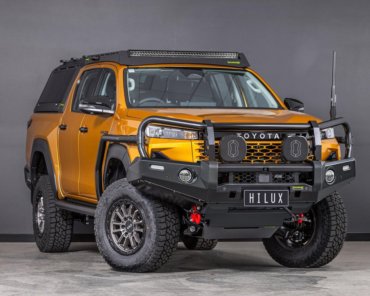 IRONMAN 4x4 Deluxe bull bar fitted to an orange Toyota Hilux Travo, front three-quarter view